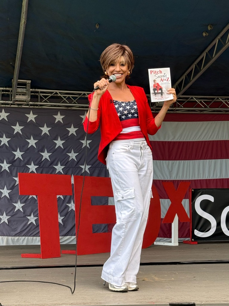 Forbes Riley on Stage holding Pitch Secrets A to Z Book